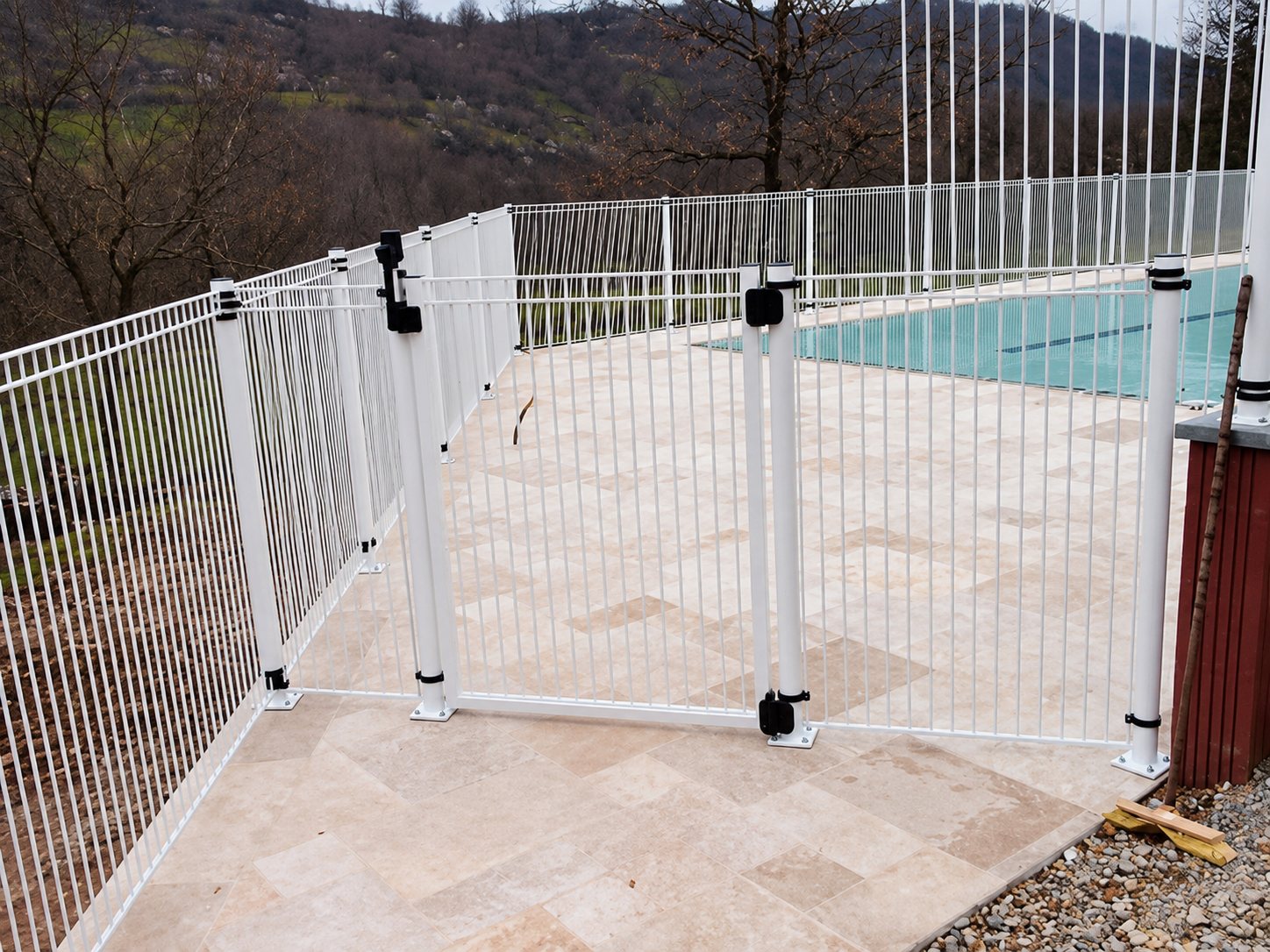 Barrière de sécurité blanche avec portillon autour d’une piscine sur terrasse en pierre