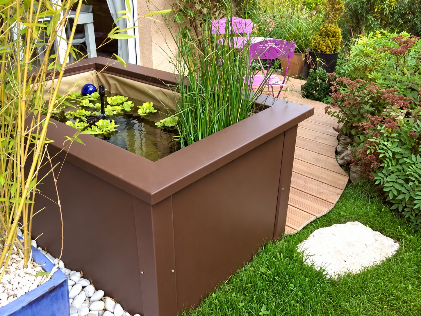 Bassin hors-sol brun avec plantes aquatiques dans un jardin avec terrasse en bois