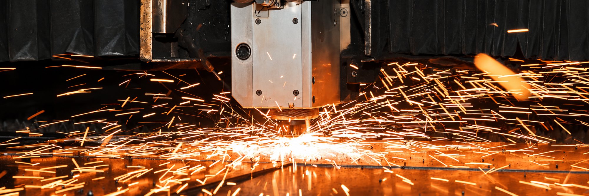 Machine de découpe laser projetant des étincelles sur une tôle métallique
