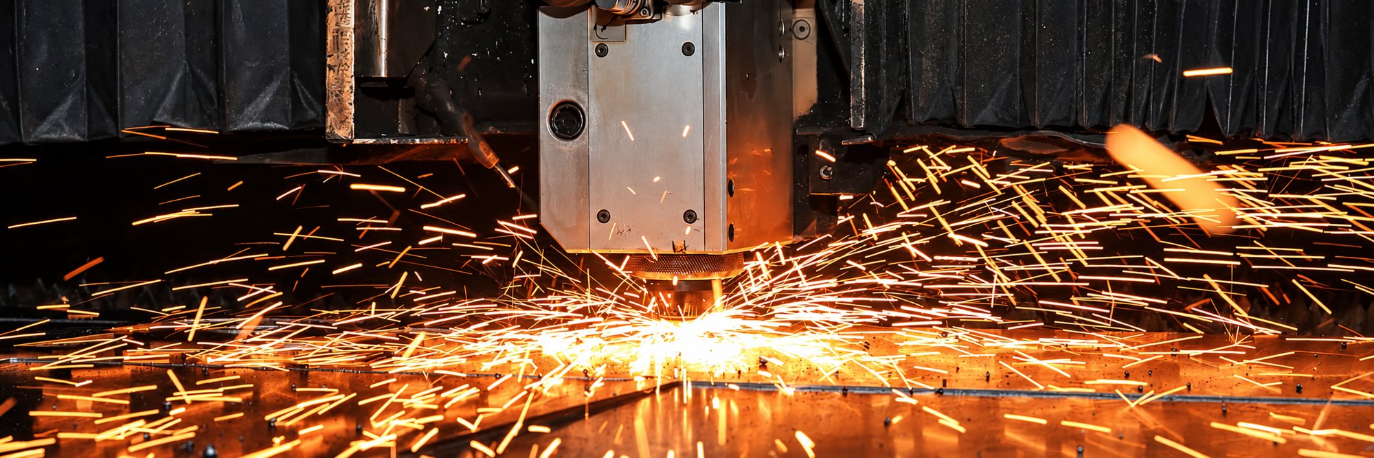 Machine de découpe laser projetant des étincelles sur une tôle métallique