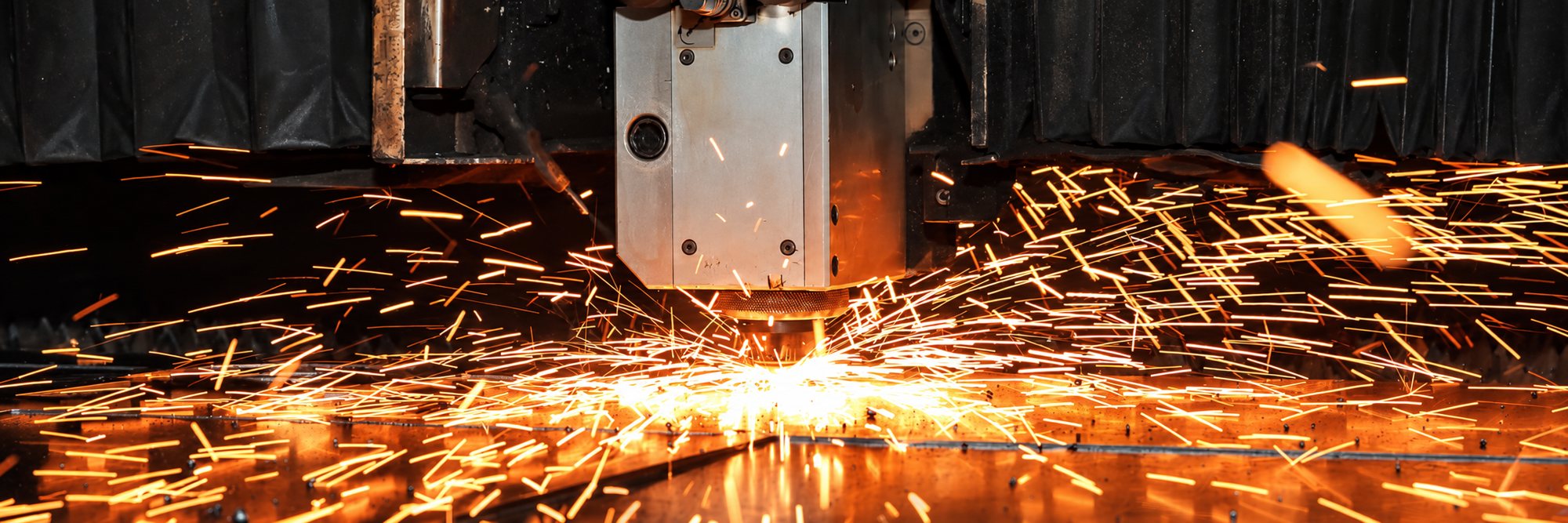 Machine de découpe laser projetant des étincelles sur une tôle métallique