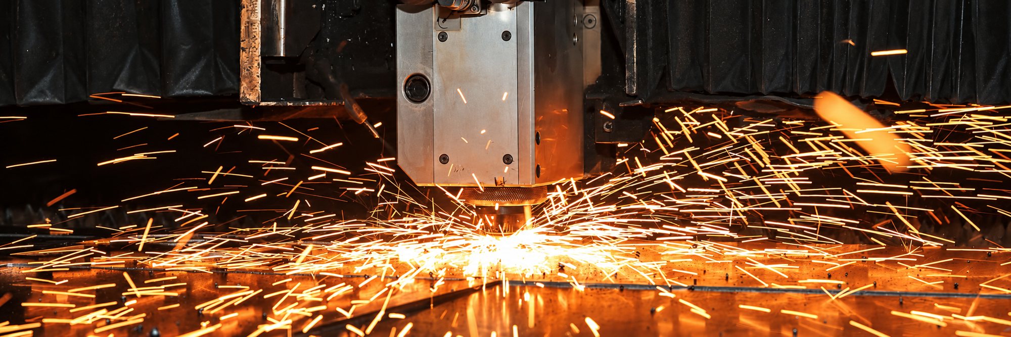 Machine de découpe laser projetant des étincelles sur une tôle métallique