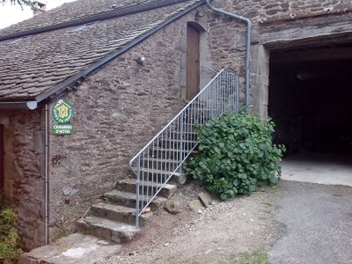 Escalier en pierre avec rampe métallique devant une bâtisse en pierre