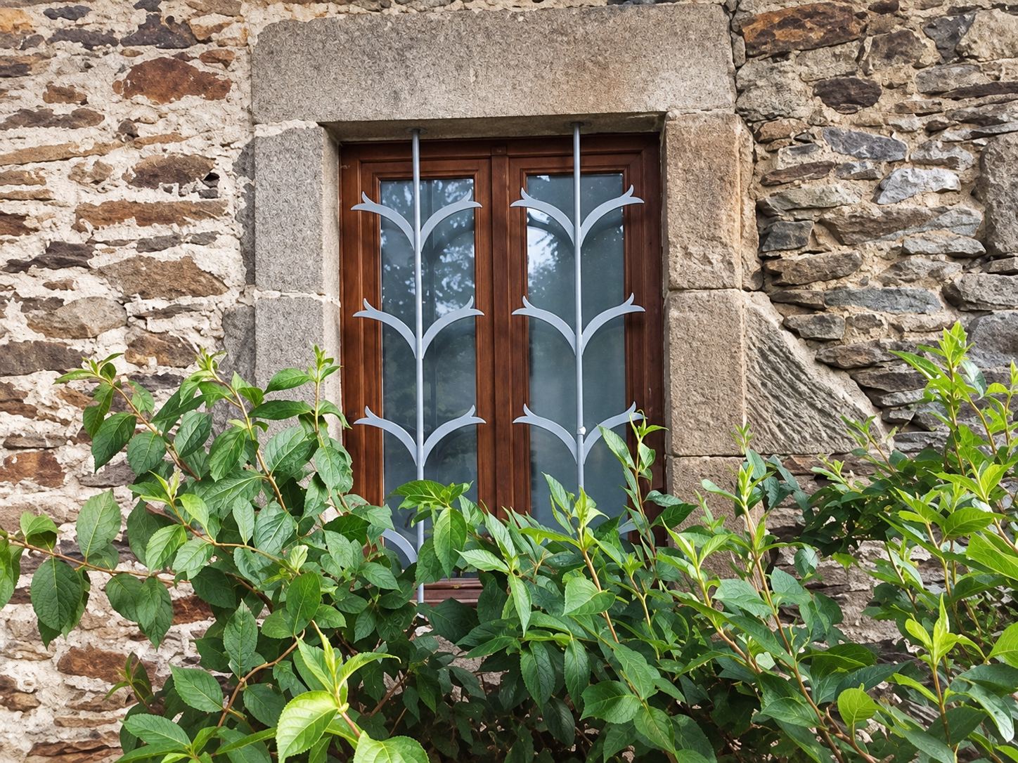 Fenêtre en bois avec grille en fer forgé dans un mur en pierre