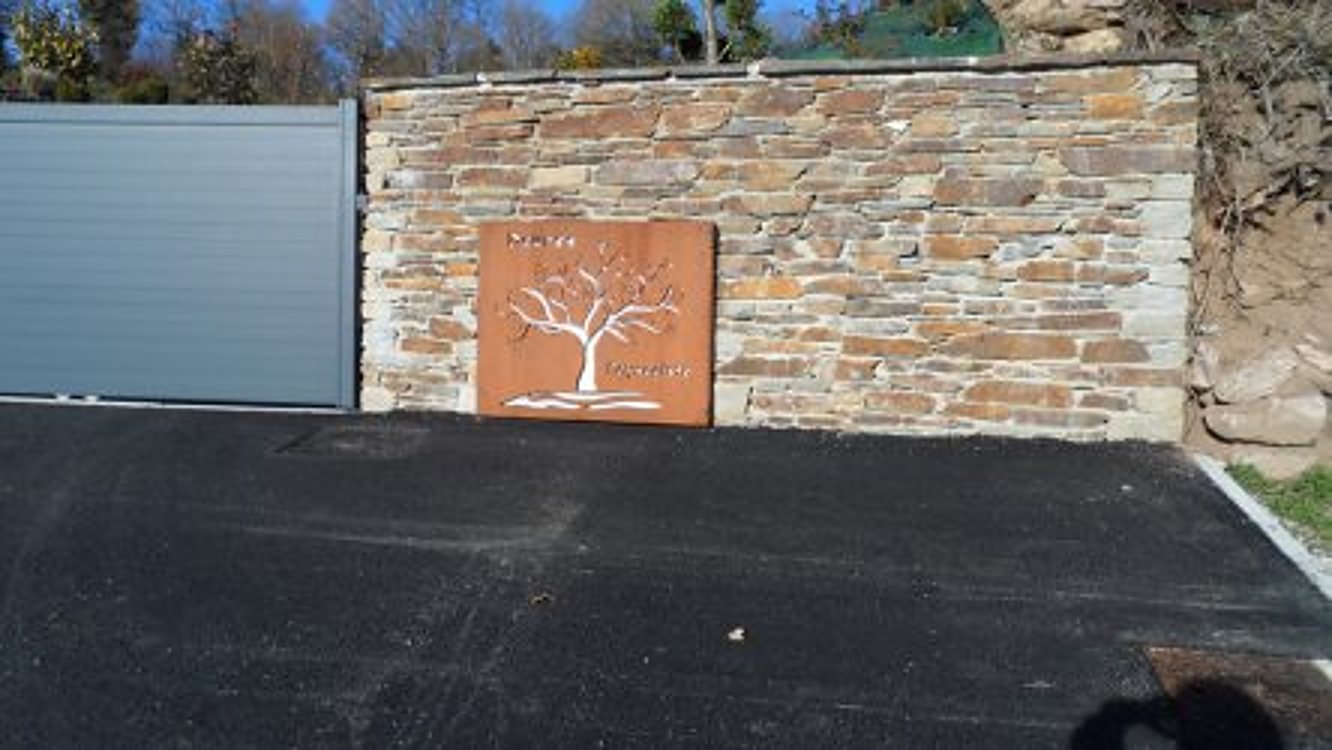 Mur en pierres sèches avec panneau métallique arbre découpé