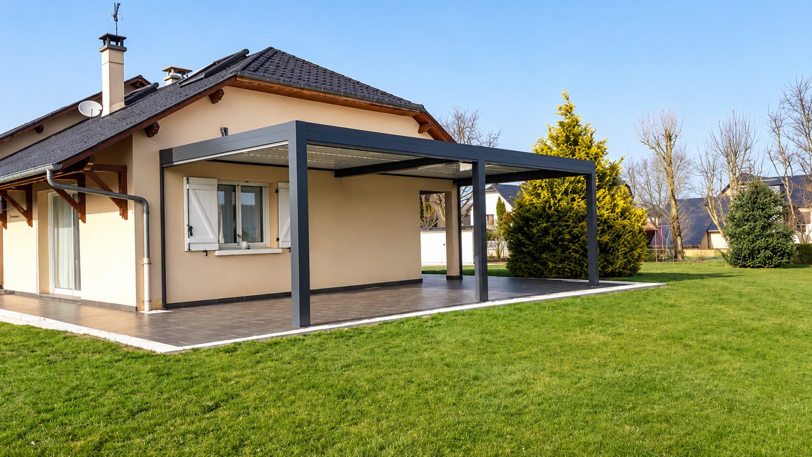 Pergola bioclimatique grise installée sur une terrasse devant une maison