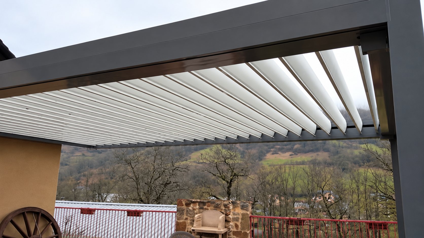 Pergola bioclimatique à lames orientables installée sur une terrasse avec vue sur la campagne