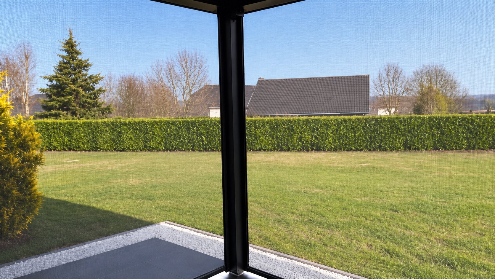 Pergola bio climatique en Aveyron, vue sur un jardin à travers une moustiquaire d’angle sur terrasse